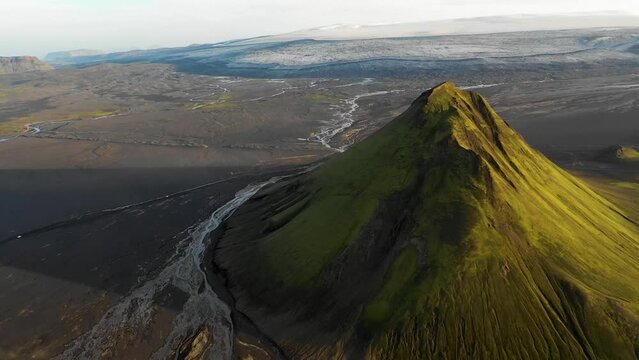 Aerial view of Maelifell mountain at sunset, a tall volcano that stands out in a desert of black sands, Iceland.