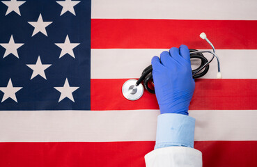 Close up shot of doctor hands placing stethoscope on united states flag - cocept showing of US labour day holiday or celebration.