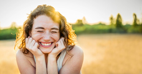 Happy beautiful woman smiling in a wheat field - Delightful female enjoying summertime sunny day...