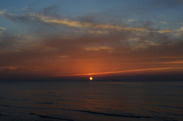 Beautiful sunset over ocean in golden hour with clouds and waves