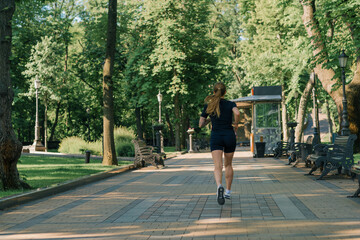 Fitness young sportswoman girl doing sports in the morning running during training outdoors in the city in the park healthy lifestyle concept