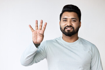 Fototapeta premium Confident Happy Smiling South Asian Man Pointing Up four fingers, number 4 Gesture for Success, Goal, Direction concept on Isolated Background