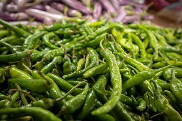 Green hot chili peppers on the counter of a vegetable market
