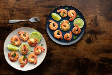 Shrimps, overhead flat lay shot on a rustic wooden background, with copy space. Cooked shrimp with lime, Mediterranean cuisine