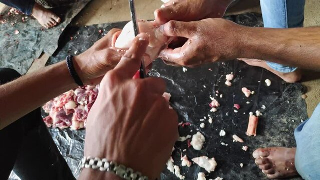 Closeup of male hands cutting a sheep testicle into smaller pieces with a knife