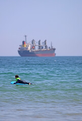 A boy lying on a surfboard in the sea, waiting for waves.