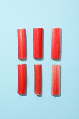 Six pieces of rhubarb stalk on blue background, top view