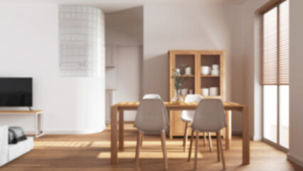Blurred background, minimal dining and living room. Wooden table with chairs, glass block wall over kitchen. Cabinets and sofa. Scandinavian modern interior design