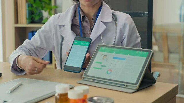 Cropped shot of female doctor in labcoat telling on camera about mobile app for monitoring health