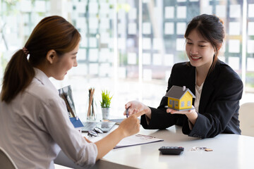 Businesswoman, real estate agent discussing the terms of the house purchase agreement contract document and letting the client sign legally, mortgage, rent, insurance.