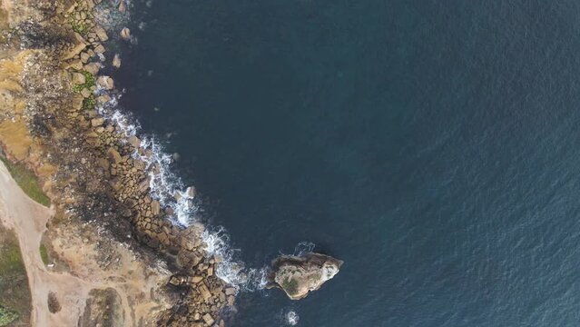 Aerial view of the wild coastline with stones at Ilheu da Papoa, a small island in Peniche facing the Atlantic Ocean, Leiria, Portugal.