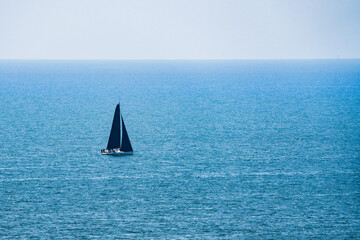 Black sailboat on the blue sea