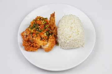 nasi ayam geprek or Spicy Geprek chicken rice culinary served on a round white plate. Most favourite dish in Indonesia.