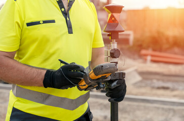 Site engineer surveyor using rugged tablet controller computer to operate EDM total station for...