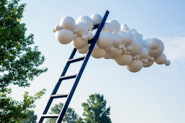 Artistic object - a ladder resting on an artificial cloud made of balloons