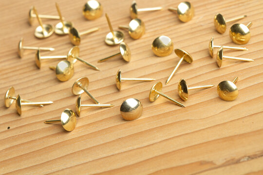 Chinchetas de metal dorado sobre un fondo de madera. Vista superior y de cerca. Copy space