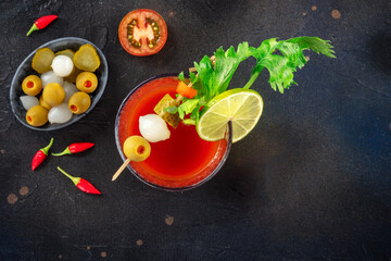 Fototapeta na wymiar Bloody Mary cocktail with garnish on a black background, overhead flat lay shot with copy space. Spicy tomato juice with alcohol, lime etc