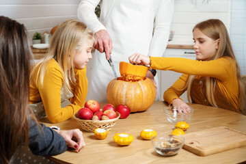 Family fun activity. Dad and daughter cut pumpkin for holiday Halloween or Thanksgiving day. Child girl takes out seeds