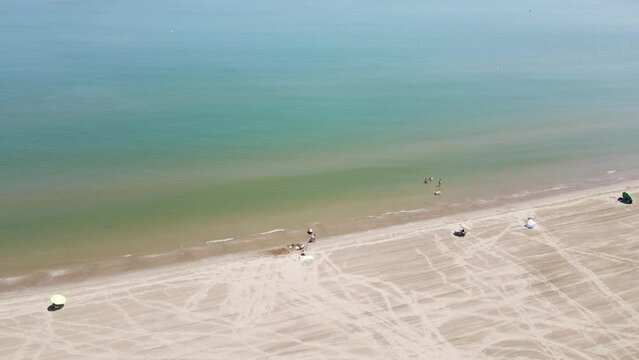 Aerial view of people with parasol on Plaja de Riumar, a beach in Delta de l'Ebre national park, Deltebre, Tarragona, Spain.