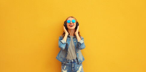 Portrait of happy smiling young woman in wireless headphones listening to music on yellow background