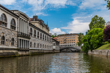 A view along the Ljubljanica River past the market towards the Triple Bridge in Ljubljana, Slovenia in summertime