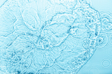 Defocus blurred blue color water ripple surface clear calm texture background with splashing bubbles water drop. Abstract and nature concept. Shiny water wave sunlight reflection shining copy space.