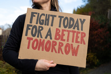 Woman holding placard sign with text Fight Today For a Better Tomorrow. Female protestor with...