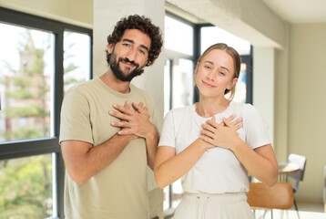 Fototapeta premium young adult couple feeling romantic, happy and in love, smiling cheerfully and holding hands close to heart