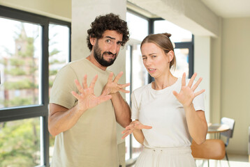 Fototapeta premium young adult couple feeling disgusted and irritated, sticking tongue out, disliking something nasty and yucky