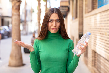 shrugging, feeling confused and uncertain. water bottle concept