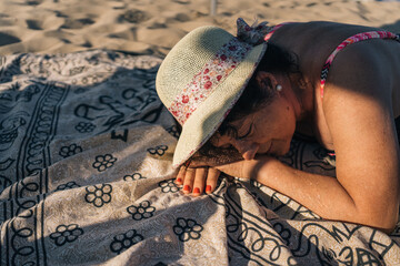 Retired senior woman on vacation falling asleep on beach towel. Senior lady lying face down on the...