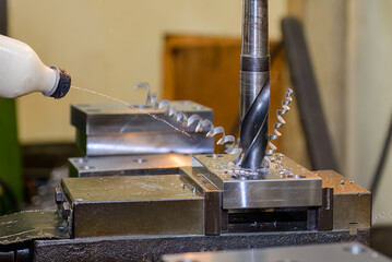 The drilling process on NC milling machine with liquid coolant manual feeding. © Pixel_B