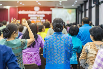 Back view of senior woman wear face mask attending and listening to the annual meeting in the auditorium. Asian elderly active participants in conference room. Joyful listeners of business conference.