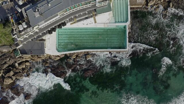 Aerial view of people swimming in a natural rock pool along the ocean coastline in Mona Vale, Sydney, New South Wales, Australia.