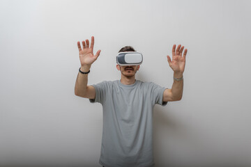 Futuristic man wearing virtual reality glasses interacts with the air in an isolated gray background.