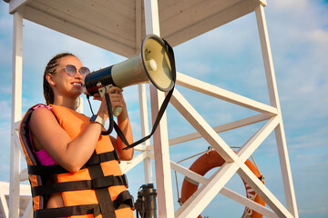 Pretty woman promoter in a life jacket talks about the sale from the rescue tower on the beach to...