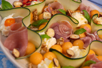 RECIPE FOR MELON, MOZARELLA, BASIL AND CURED HAM SALAD, CUCUMBER SLICE, ORANGE VINAIGRETTE. High quality photo