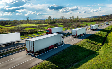 Convoys of transportation Trucks in lines passing each other on a rural countryside highway under a beautiful blue sky - obrazy, fototapety, plakaty