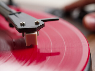 Close-up. Record player needle on red vinyl record. Advertising for a recording studio, music store, equipment. © Anton