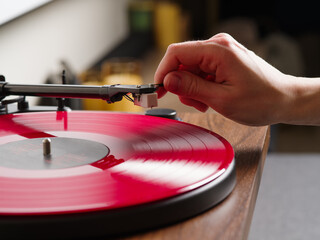 A woman's hand turns on a turntable with a red vinyl record. Close-up. DJ, night club, disco....