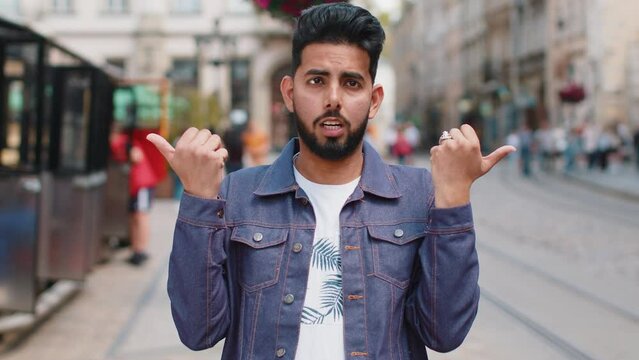 I dont know what to say. Confused young indian man feeling embarrassed about ambiguous question, having doubts, no idea, being clueless uncertain. Hindu guy walking in urban city street outdoors