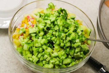 Diced cucumber, crab sticks, corn in a clear salad bowl
