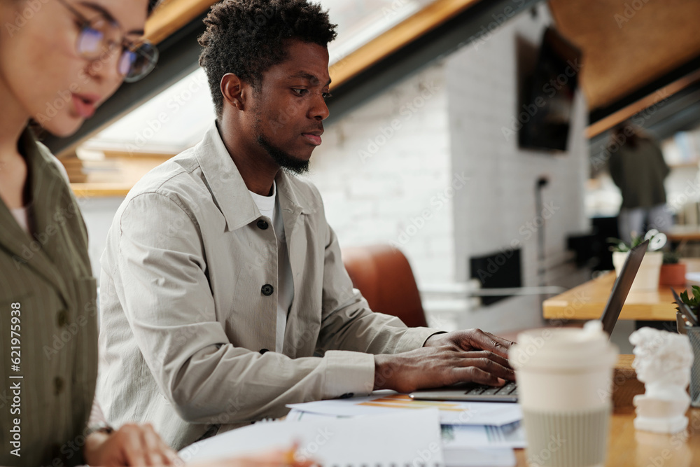 Poster focus on young african american analyst typing on laptop keyboard and looking through online data on