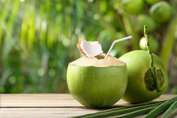 Cool coconut juice on wooden table with coconut tree background.