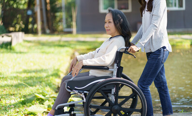 Asian senior woman in wheelchair with happy daughter. Family relationship retired woman sitting on...