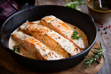 Cooked salmon fish with cream sauce in frying pan