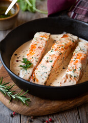 Cooked salmon fish with cream sauce in frying pan