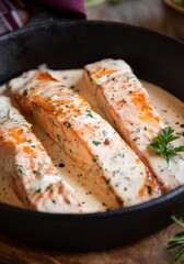 Cooked salmon fish with cream sauce in frying pan
