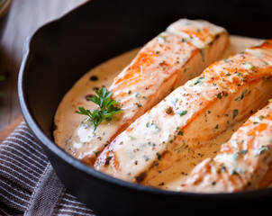 Cooked salmon fish with cream sauce in frying pan