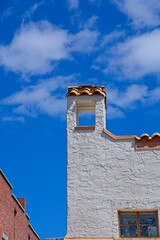 Terracotta roof tiles on stucco building tower adjoining brick building against blue skies